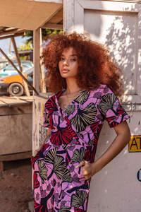 卷发女子身着紫红印花连衣裙街拍