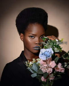 深色妆容女子手捧花束凝视镜头