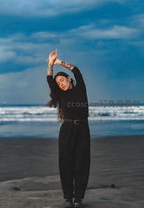 黑衣女子海边伸展双臂享受宁静时刻