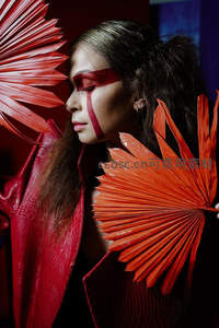 红妆女子手持扇叶，神秘面庞如戏剧角色