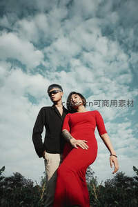 蓝天白云下情侣相拥，红裙黑衫成焦点