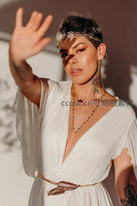 纹身女郎白裙配金饰阳光下挥手