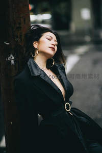 街角倚柱的静谧时光，黑色风衣与金色耳环的都市格调