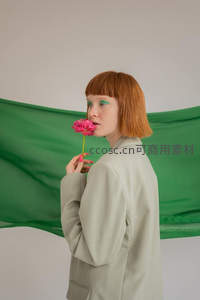 红发女子手持粉色花朵侧颜特写