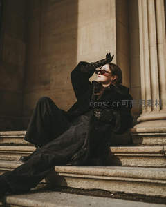 墨镜女子坐石阶古典建筑前摆姿