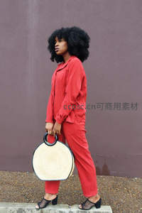 红衣女郎手提草编包漫步