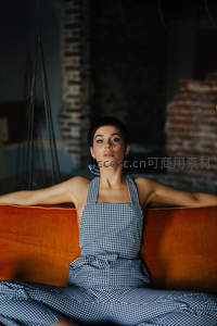 格纹连衣裙女子慵懒倚坐橙色沙发