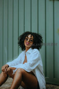 卷发美女绿色墙前慵懒坐姿