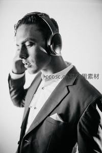 西装男子佩戴耳机沉思侧影