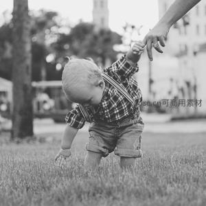 幼童在草地上蹒跚学步，大人温柔牵引