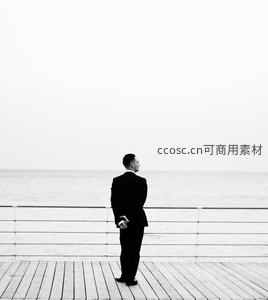 海边木栈道上西装男子远眺海天一线