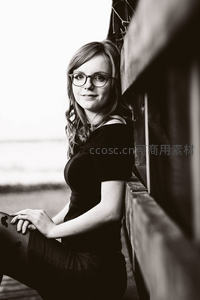 戴眼镜女孩倚靠木栏微笑