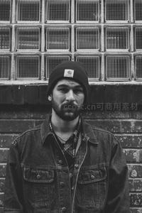 街头男子戴帽凝视，复古砖墙