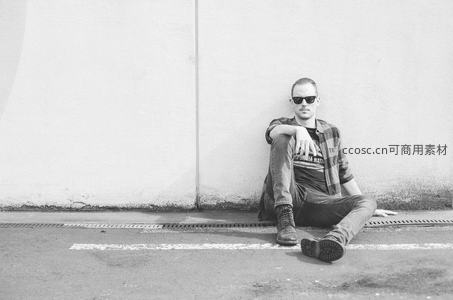 墙边坐姿酷帅的墨镜青年