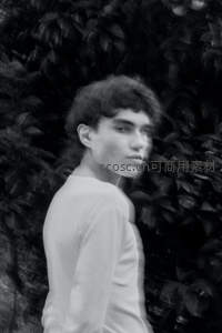 绿植背景前回眸的青年男子