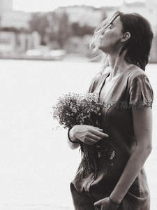 湖畔微风中捧花的女子侧影