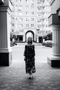 建筑拱门下漫步的花裙女子