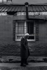 老人低头走过老旧街巷墙边