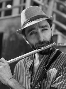 街头乐手：戴帽男子专注吹奏长笛