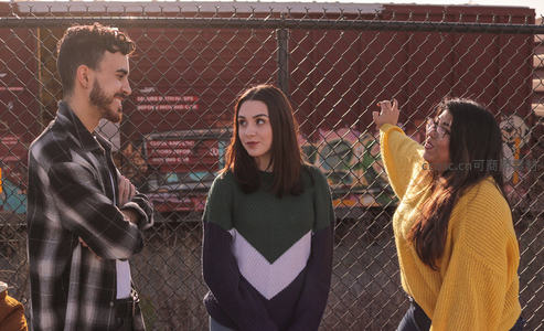 铁丝网前三位朋友轻松交谈