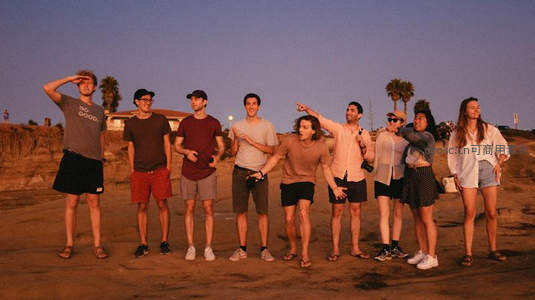 夕阳下沙滩上一群年轻人合影留念