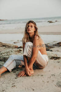 海边岩石上静坐的金发女