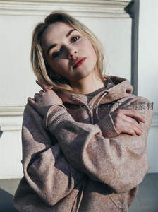 阳光墙角的慵懒卫衣女孩