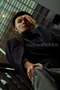 时尚青年戴帽倚坐，链条装饰显个性