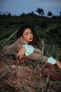 暮色草丛中卷发女郎倚卧