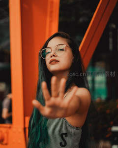 绿发女孩伸出手掌面对橙色建筑