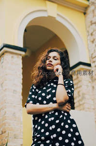 拱门下的波点裙少女，卷发微扬尽显复古优雅