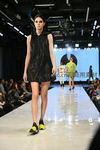 T台模特身着亮面无袖连衣裙，步伐自信向前