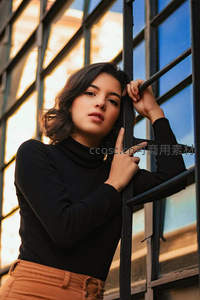 黑衣女子倚靠铁窗光影交错