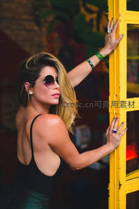 墨镜美女倚靠黄色门框回眸