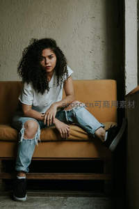 破洞牛仔裤少女坐橙色沙发