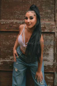 黑发高马尾少女倚靠木墙微笑