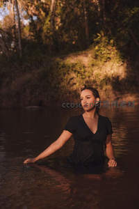 黑裙女子静坐溪流中沐浴夕阳