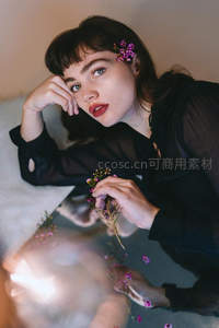 黑衣女子手捧小花，镜面倒影营造梦幻氛围