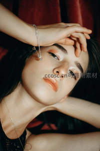 深色背景下雀斑少女手抚额头特写