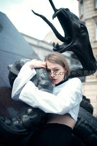 少女倚靠龙形雕塑凝视镜头