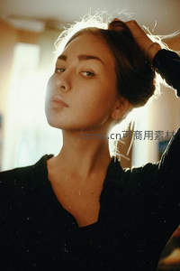 逆光中女子整理秀发姿态优雅