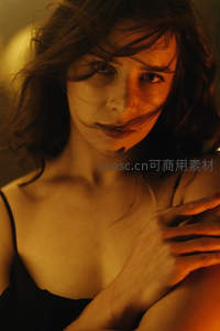 暖光下的沉思女性，发丝轻拂脸颊