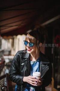 街头阳光下的时尚女郎手捧咖啡