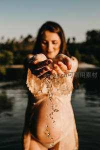 孕妈轻捧水珠，阳光洒落温柔瞬间