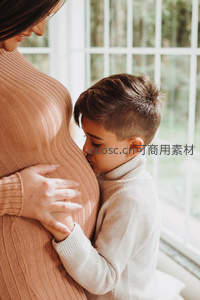 窗边男孩亲吻妈妈孕肚，温情脉脉