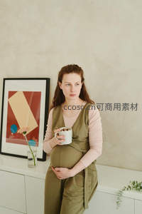 孕妇靠柜持杯凝视镜头神情安然