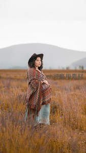 田野中孕妇披彩毯，远山为伴