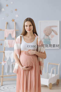 温柔孕妈轻抚腹部，粉色家居温馨如画