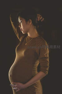 暖光侧影孕妇凝视孕肚