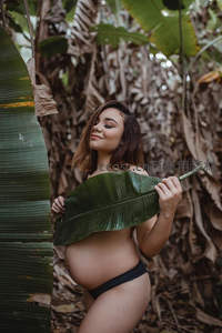 热带雨林中孕妇怀抱绿叶微笑